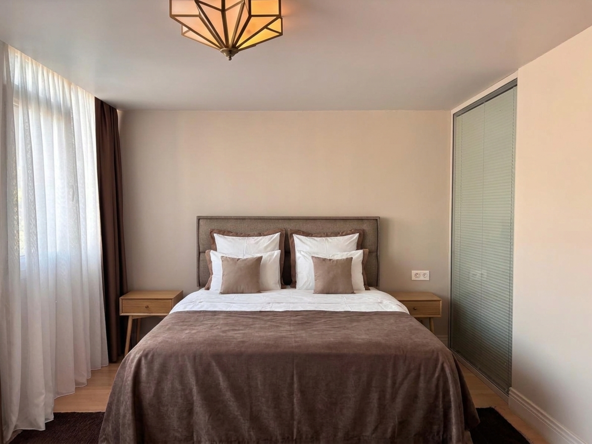 Bedroom with double bed, curtained window and wardrobe.