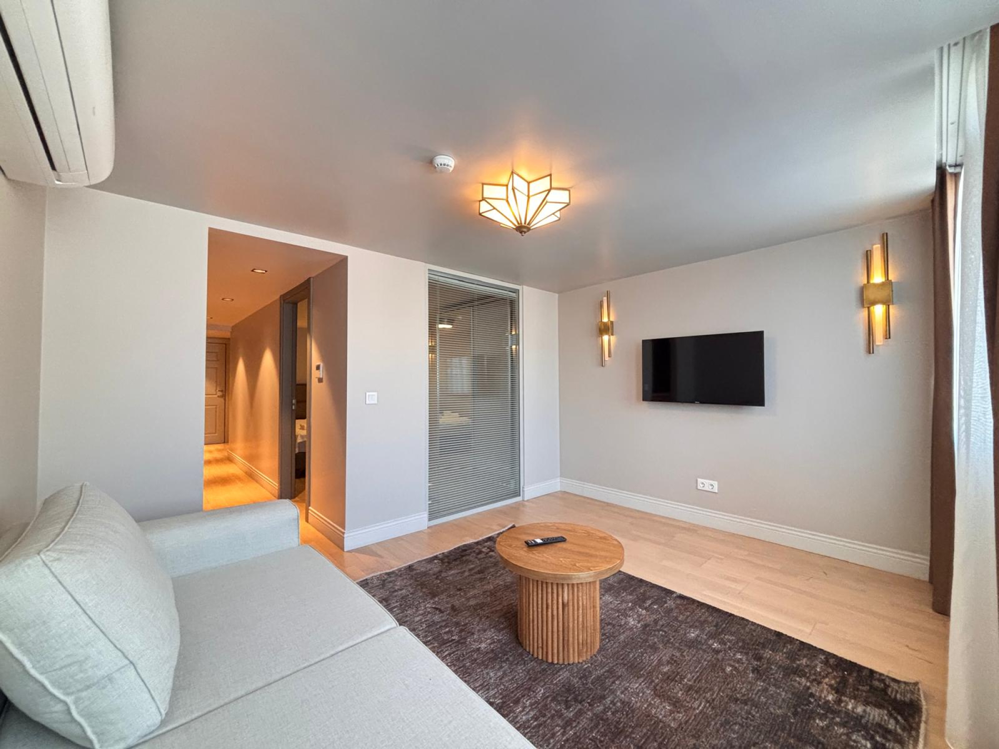 Living room with corner sofa, coffee table and wall-mounted TV.