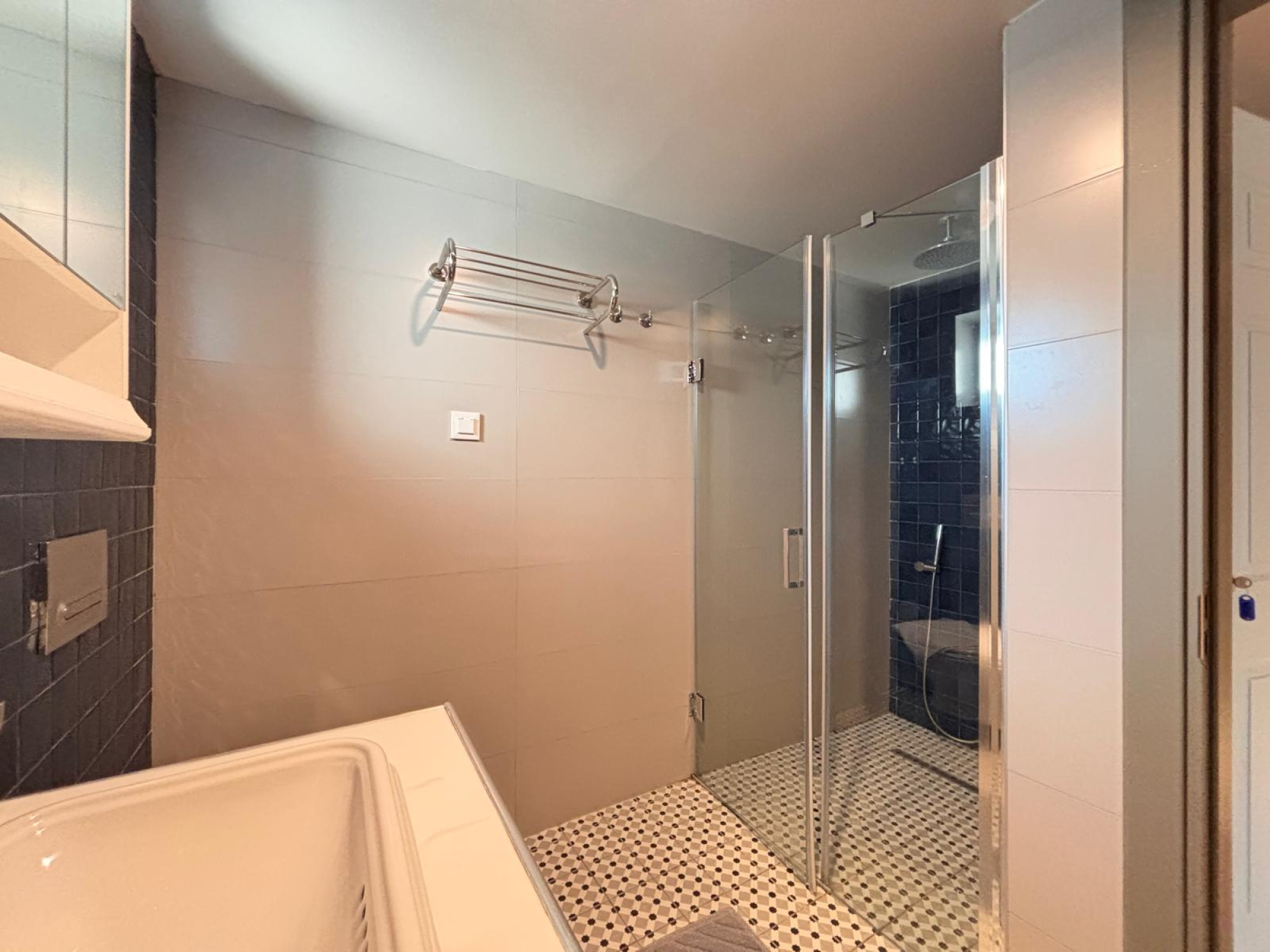 Bathroom with glass walk-in shower, vanity and light tile.