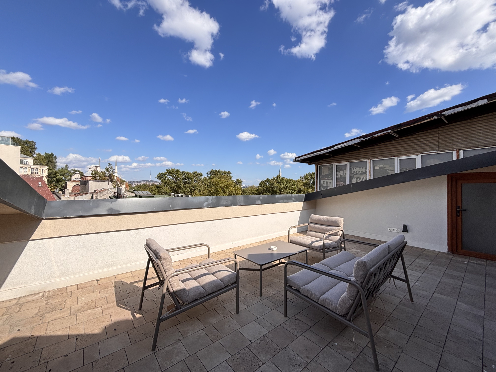 Rooftop terrace with open sky and neighborhood outlook.